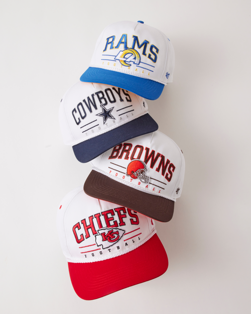 Four sports team-themed baseball caps stacked on a white background