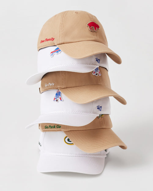 Stack of tan and white baseball caps with various logos on a white background
