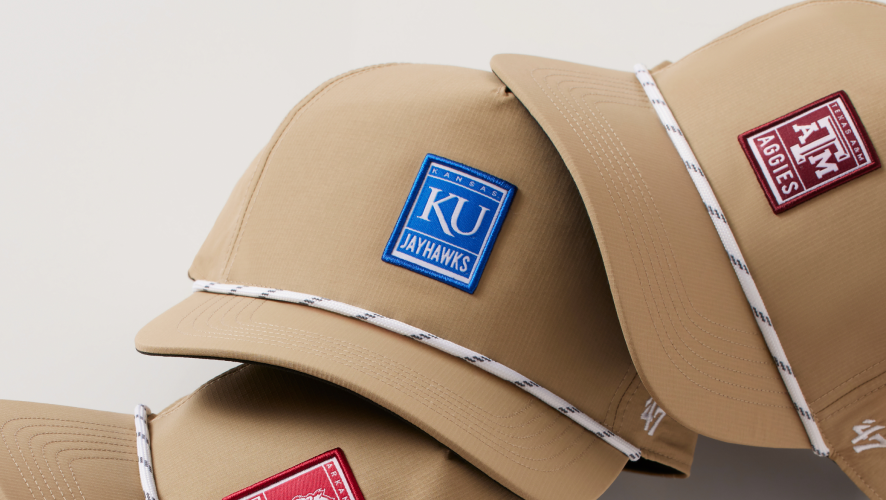 Two tan baseball caps with different logos on a neutral background