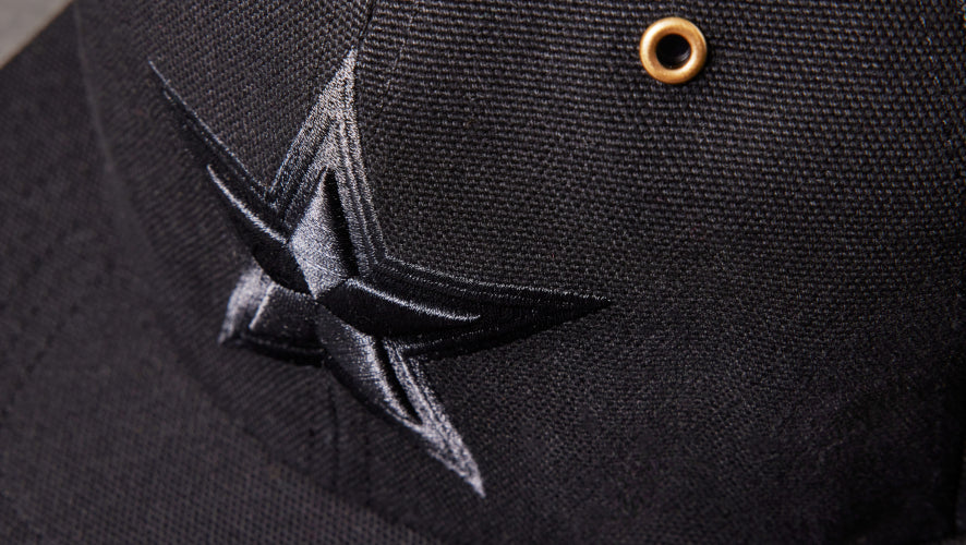 Black cap with a star emblem and gold button on a dark background