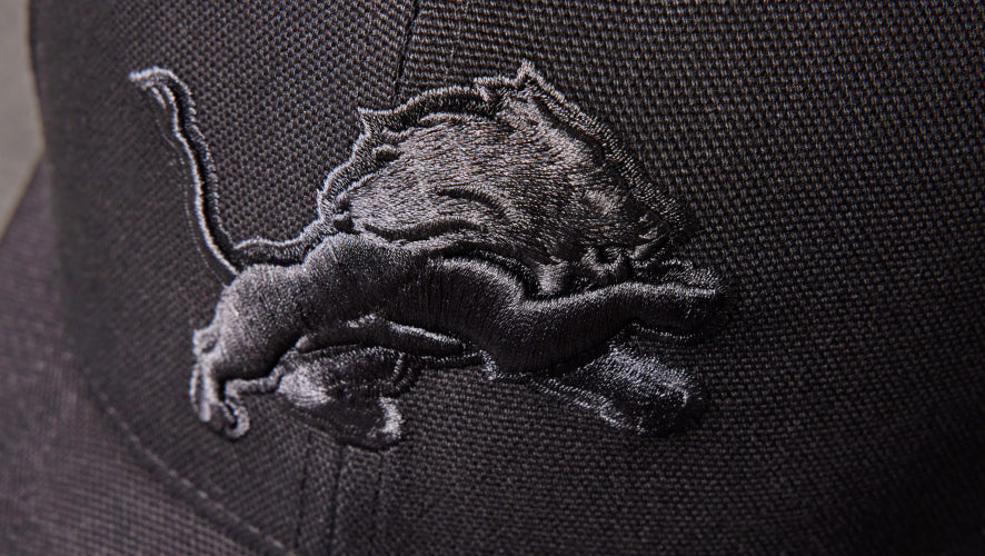 Black embroidered lion logo on a dark fabric background