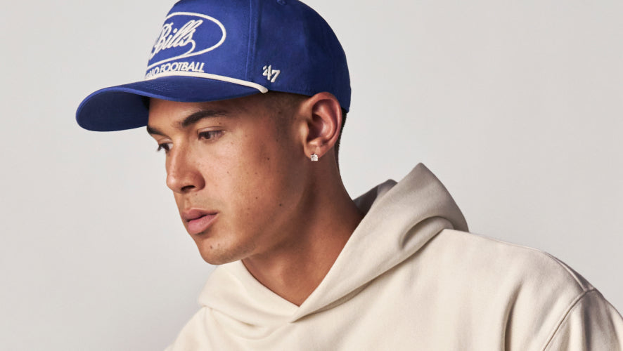 Person wearing a blue cap with a logo on a plain background