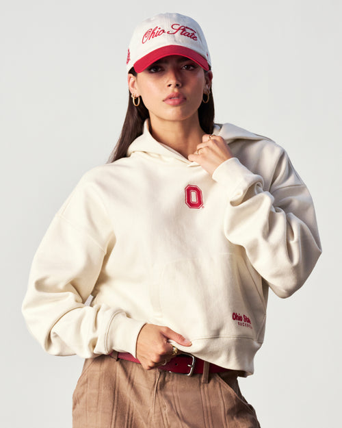 Person wearing a white hoodie with a red logo and a matching cap on a light gray background