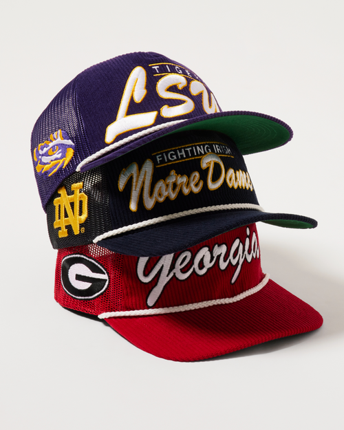 Three sports team-themed caps stacked on a white background