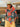 Woman standing in front of a car with a light green Los Angeles hat on and a blue Lasolona, Angeles Dodgers, short sleeve T-shirt, and a crochet, gray and orange striped sweater wrapped around her shoulders