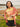 A woman on the beach, wearing a St. Louis Cardinals short sleeve yellow T-shirt, and a orange and white striped sweater wrapped around her shoulders