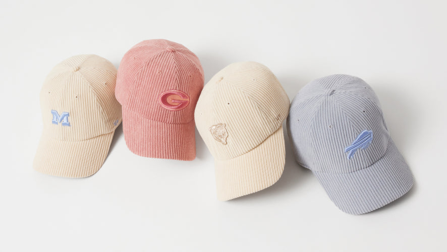 Four baseball caps in beige, pink, cream, and gray on a white background