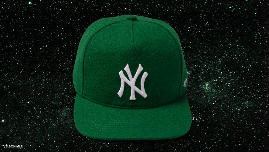 Green New York Yankees wool cap from the Zodiac Collection, shown on a sparkly black starry background.