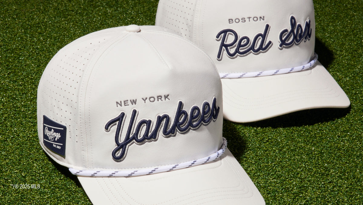Two white rawlings hats on the golf green (yankees and red sox)
