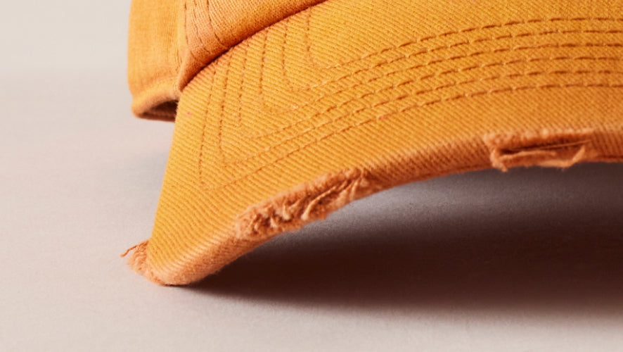 Close-up of a mustard yellow cap on a light gray background