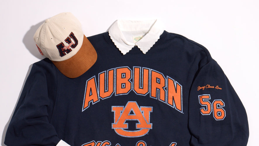 Navy blue Auburn sweatshirt with orange lettering and a cap on a white background