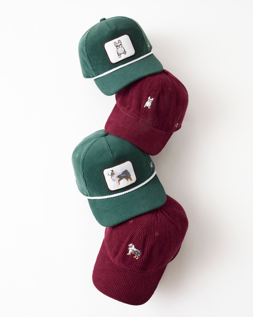 Two green caps and two red hats with dog graphics stacked on a white background.
