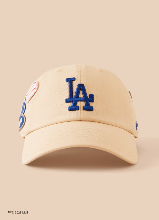 Beige baseball cap with blue 'LA' logo on a beige background