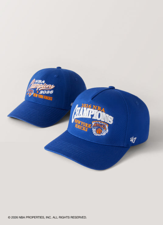 Two blue caps with NBA Champions 2026 text on a light gray background