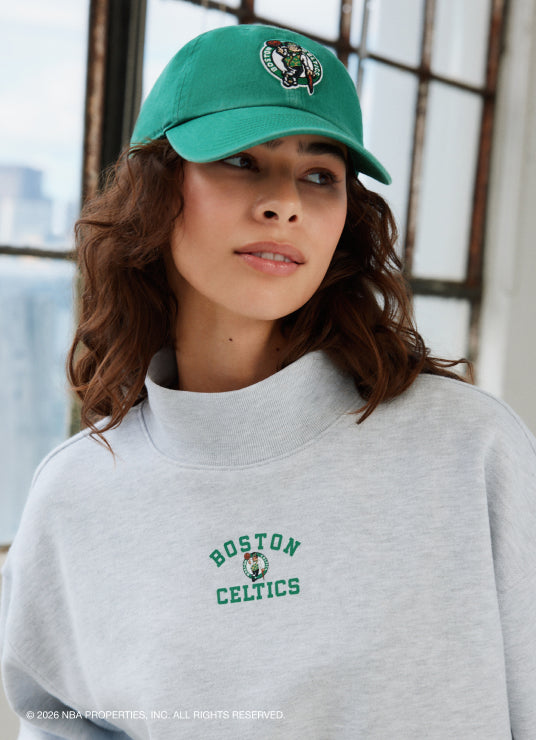 Person wearing a green Boston Celtics cap and gray sweatshirt with team logo.
