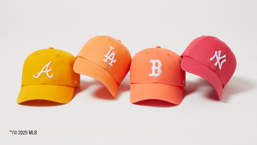 Four baseball caps in yellow, orange, red, and pink with MLB logos on a white background.