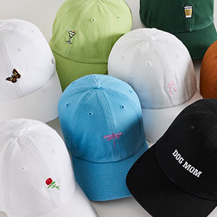 Different colored hats with small embroidered icons including rose, butterfly, and Dog Mom. 