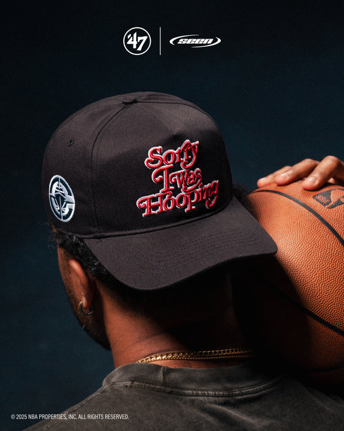 Person wearing a black cap with red text and a logo, holding a basketball on a dark background. '47 x seen logos