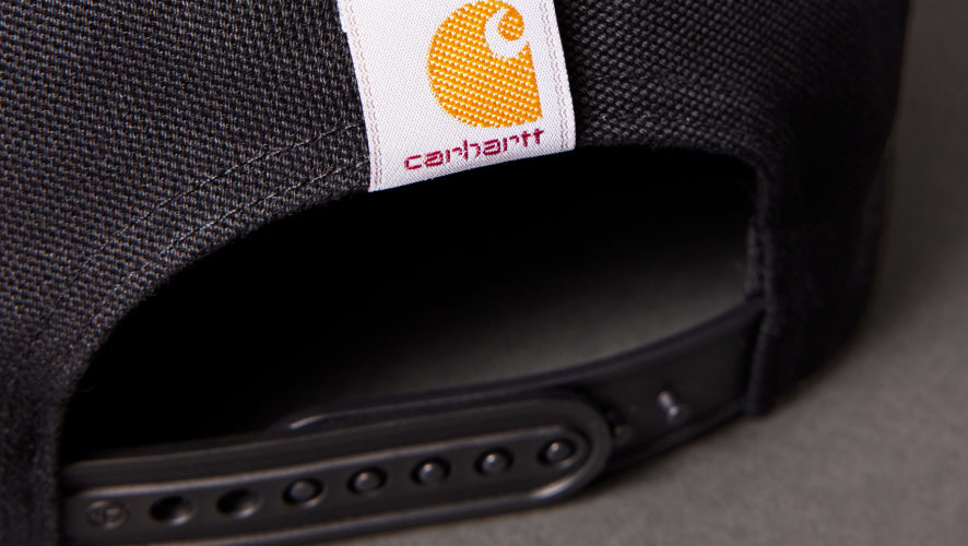 Close-up of a black cap with a Carhartt logo on a gray background