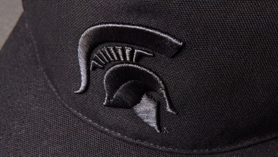 Black cap with a Spartan helmet logo on a dark background