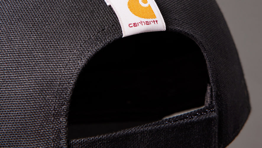 Close-up of a black cap with a Carhartt logo on a gray background