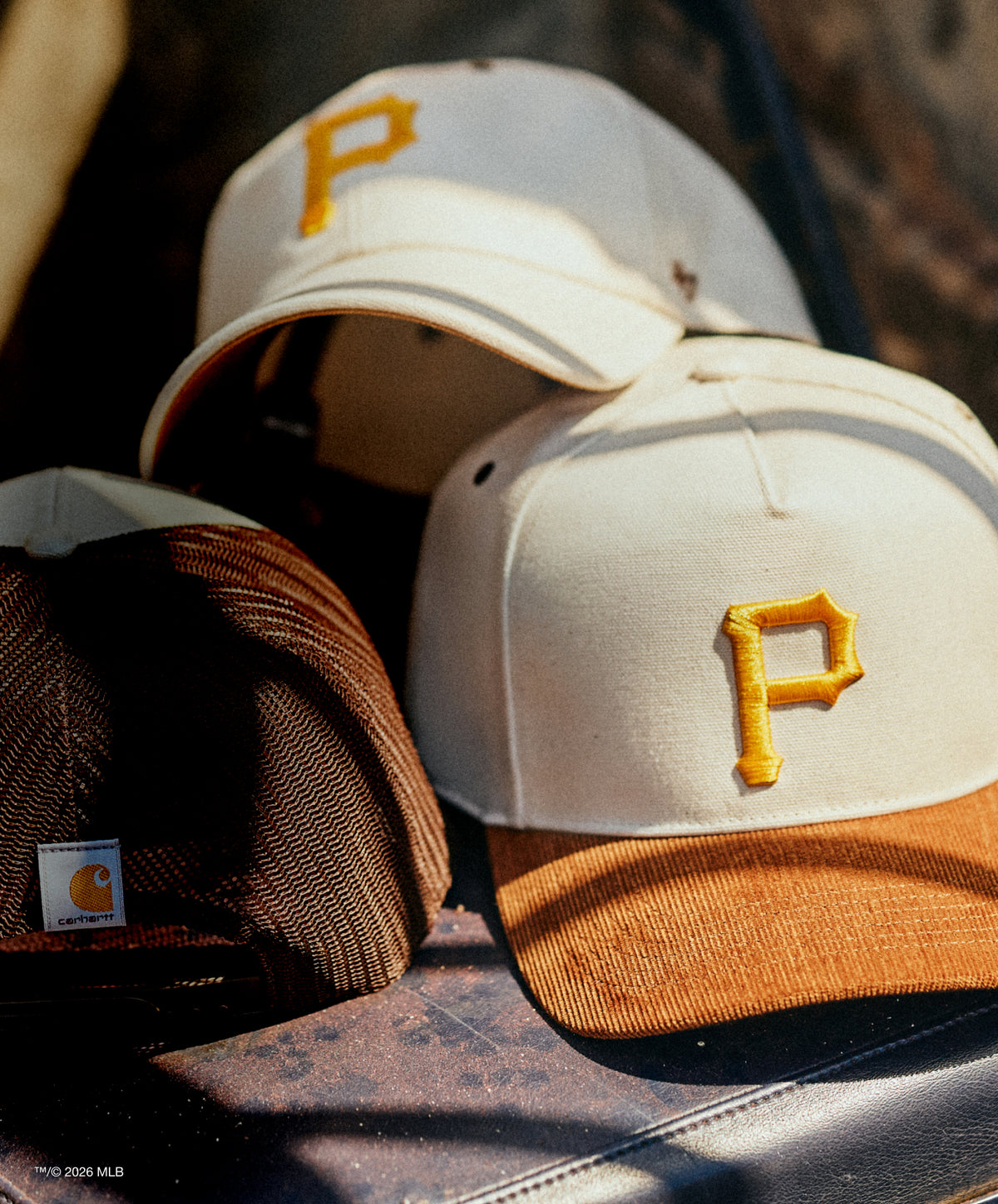 Two baseball caps with a yellow 'P' logo on a textured surface