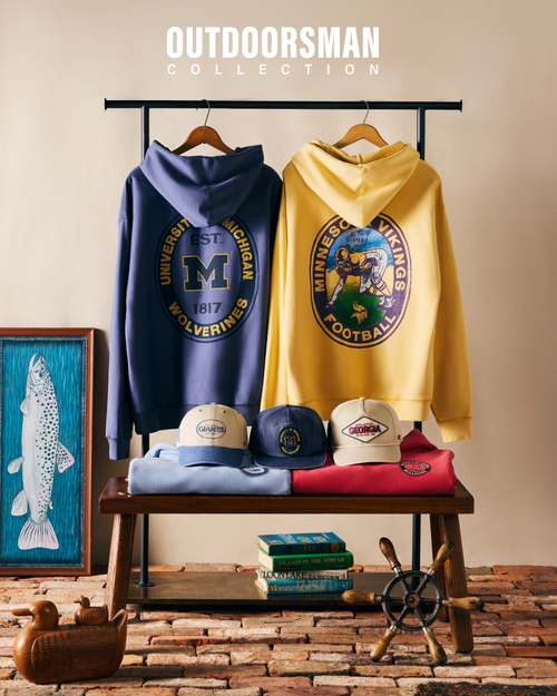 Outdoorsman Collection featuring hoodies, hats, and a t-shirt on a wooden bench with a rustic background.
