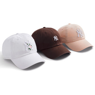 Three women’s Yankees hats by ‘47 Brand in white, brown, and blush pink, featuring floral embroidery and classic NY logos in soft dad hat silhouettes.