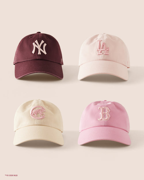 Four baseball caps with different team logos on a light background