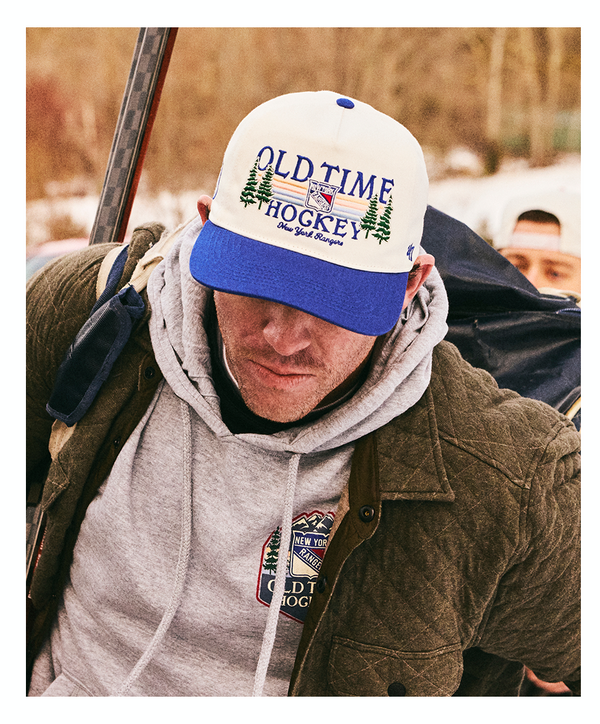 Man wearing an 'Old Time Hockey' cap outdoors with a blurred background