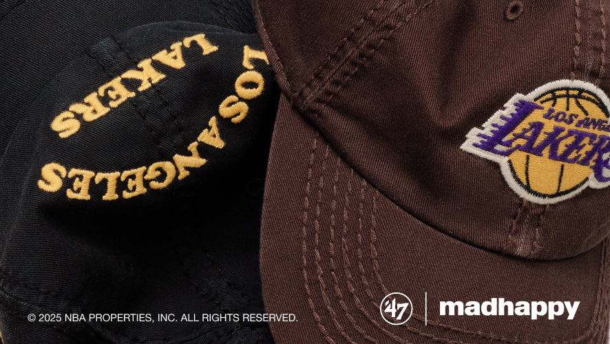 Two Los Angeles Lakers caps, one black and one brown with logo, on a dark background.