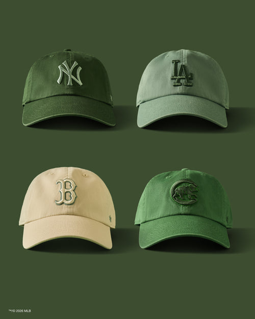 Four green baseball caps with different logos on a green background