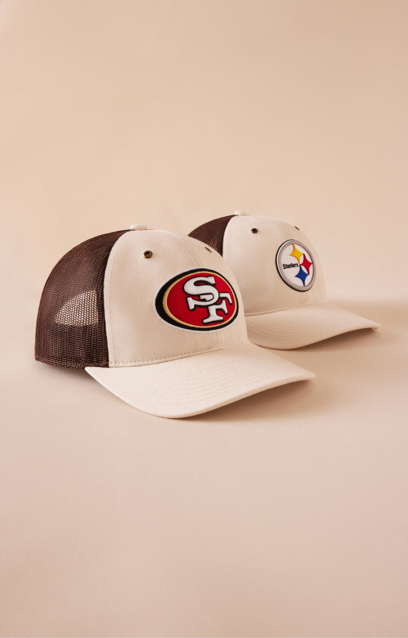 Two baseball caps with sports team logos on a beige background