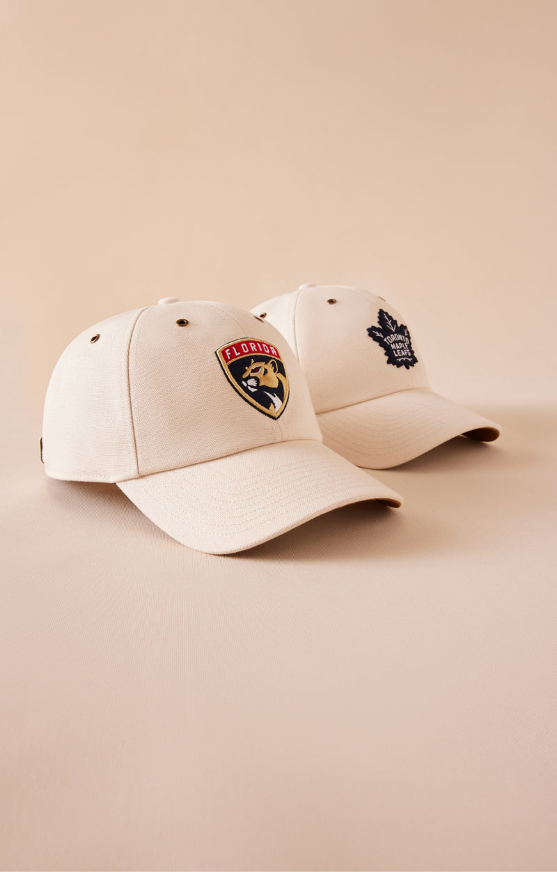 Two white baseball caps with logos on a beige background