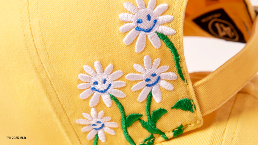 Detail image of a yellow hat with embroidery of white flowers on the back.