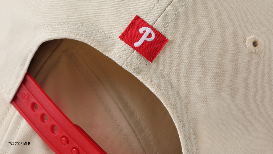 detail image of the back of a hat showing a phillies logo and red snapback closure. 