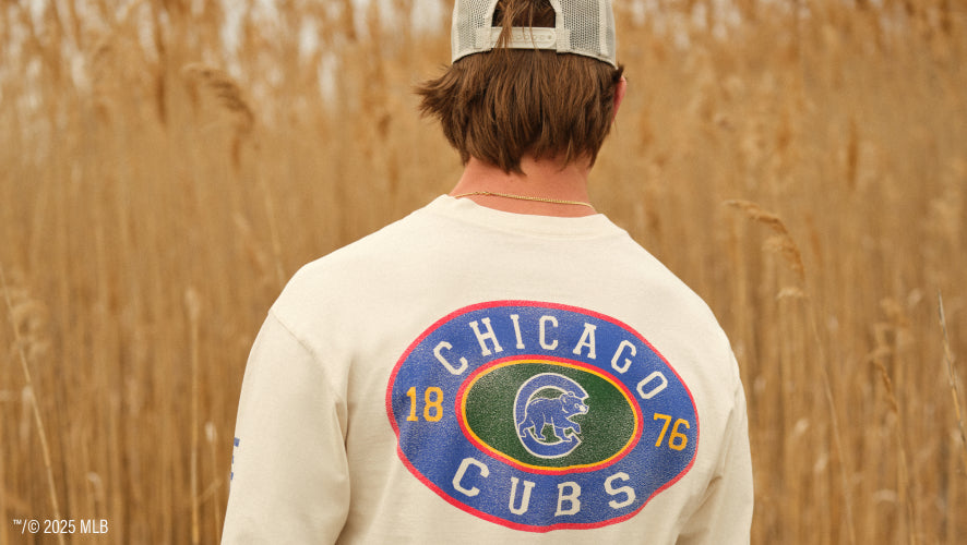 Man on the beach with a Chicago Cubs tee shirt and hat on. 
