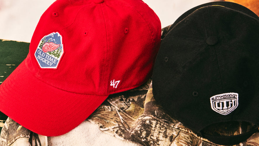 Red and black baseball caps with logos on a camouflage background