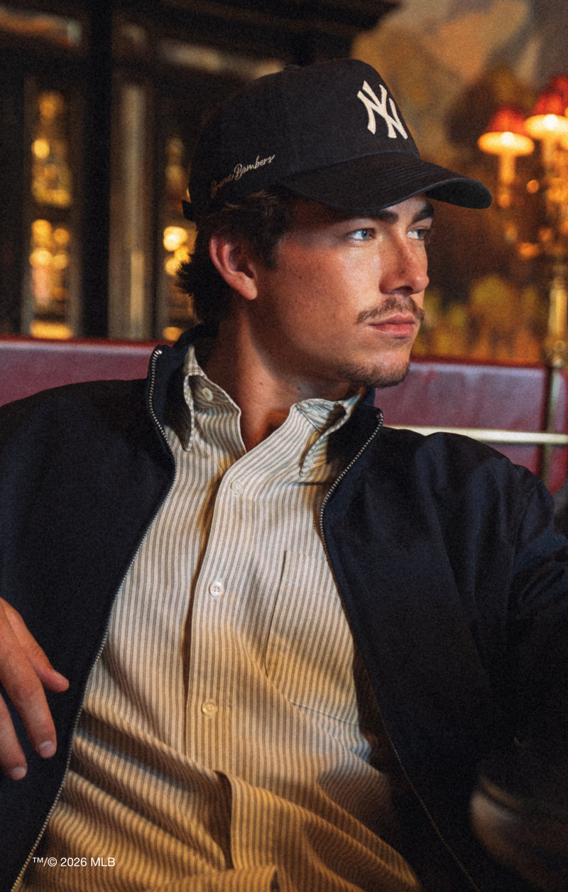 Man wearing a black cap with a logo, sitting in a bar setting.