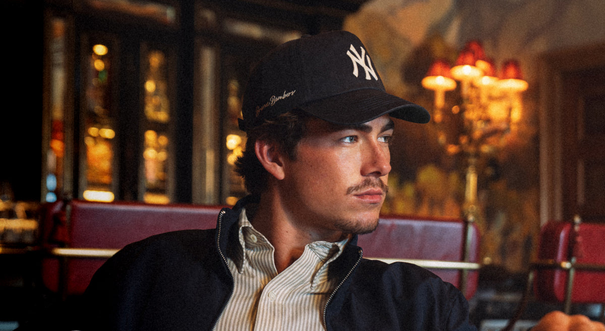 Man wearing a black cap with a logo in a dimly lit restaurant setting