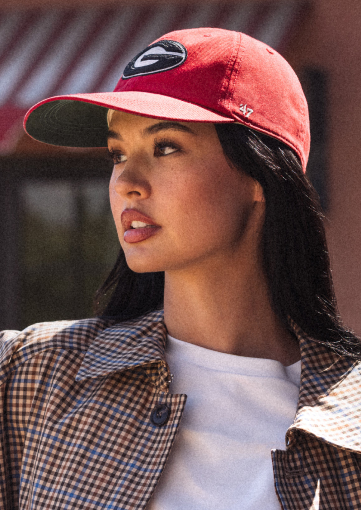 Person wearing a red cap with a logo, plaid jacket, and white shirt.