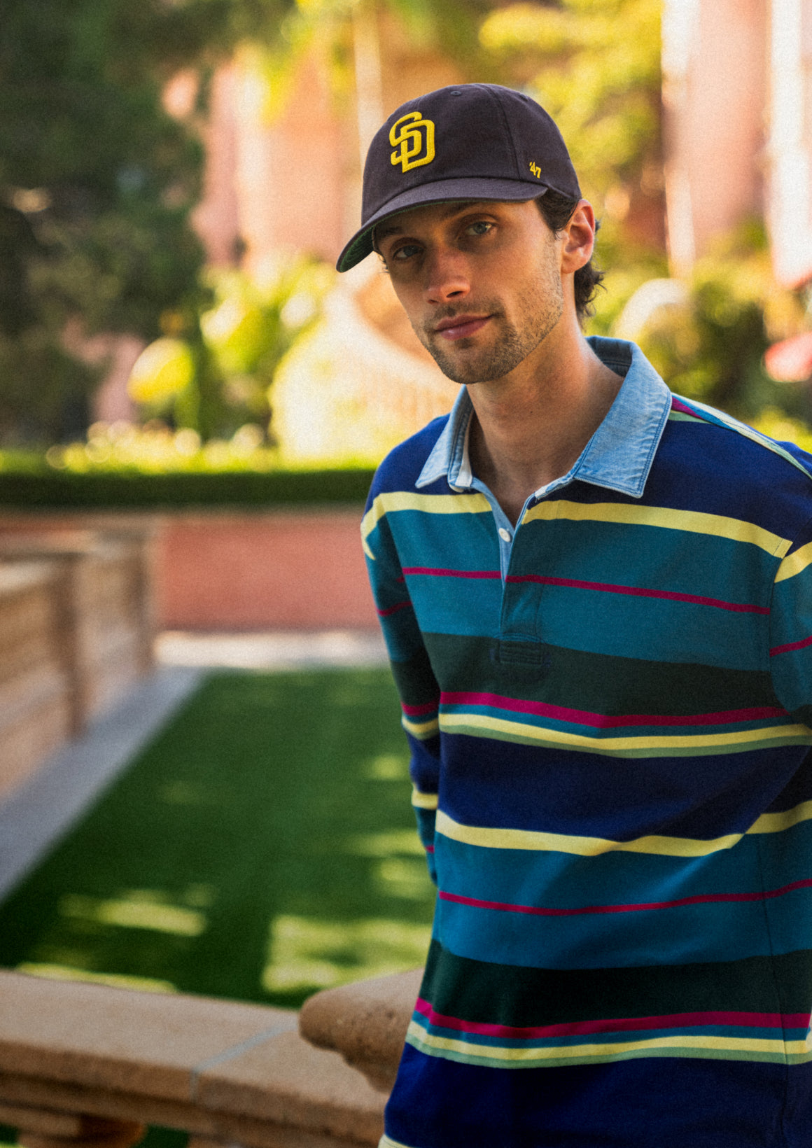 Man wearing a striped polo shirt and cap outdoors