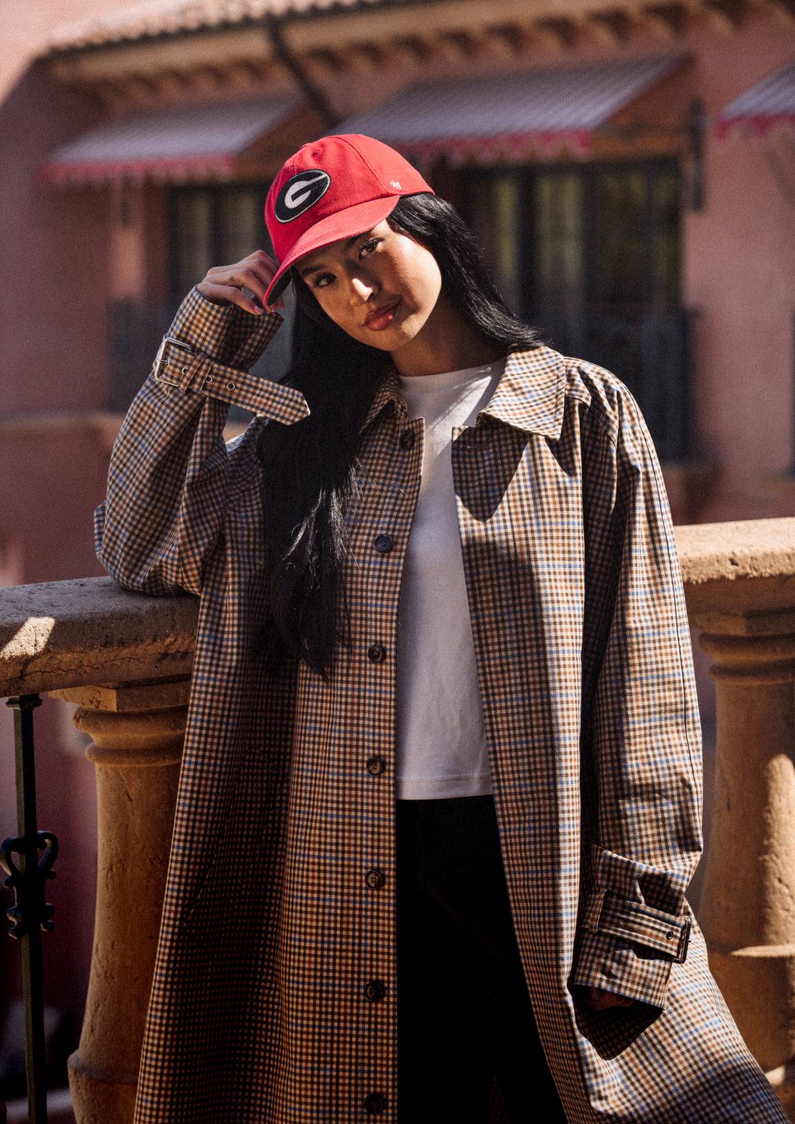 Person wearing a plaid coat and red cap with a logo, standing outdoors.