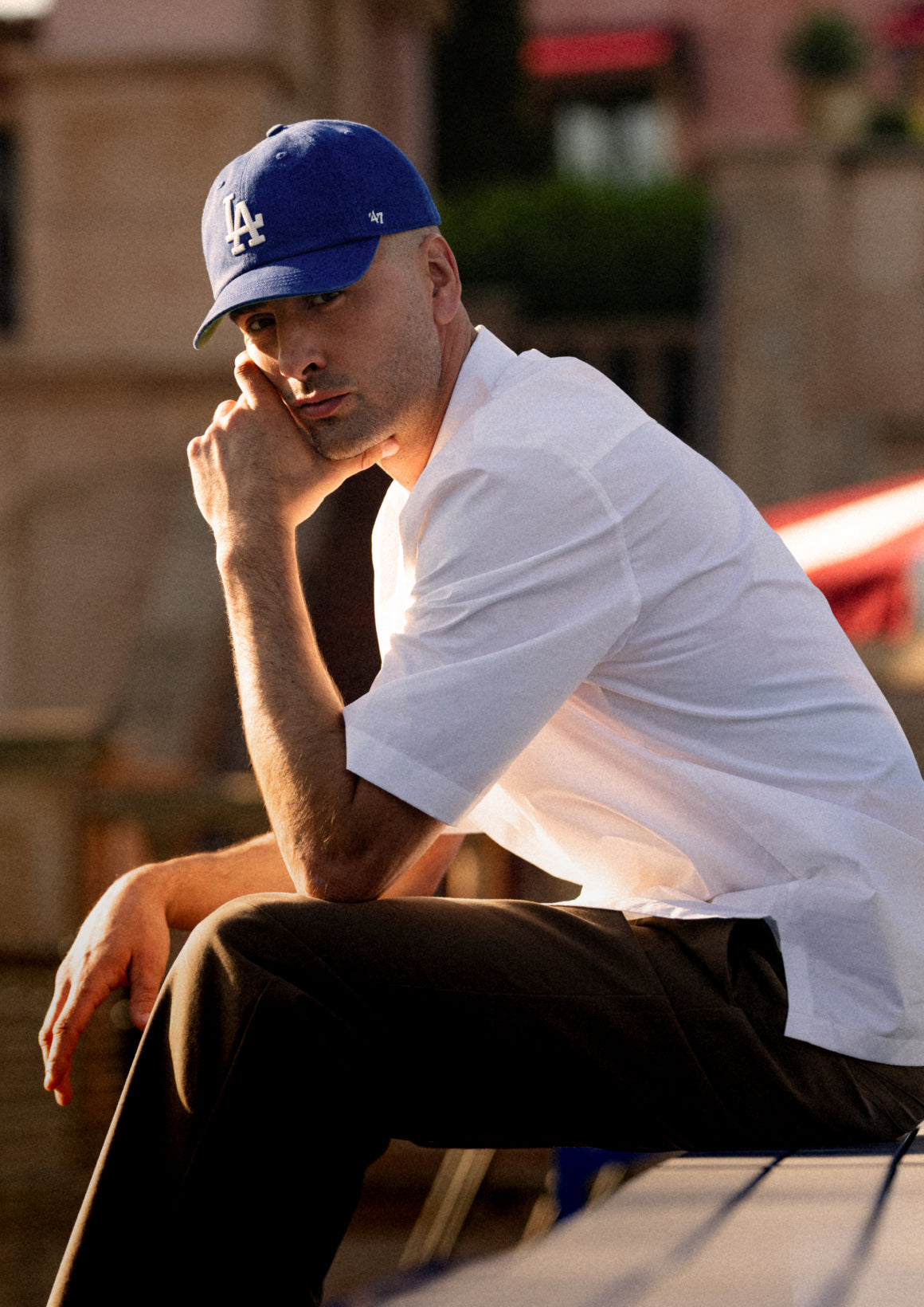 Man wearing a blue cap and white shirt sitting outdoors.