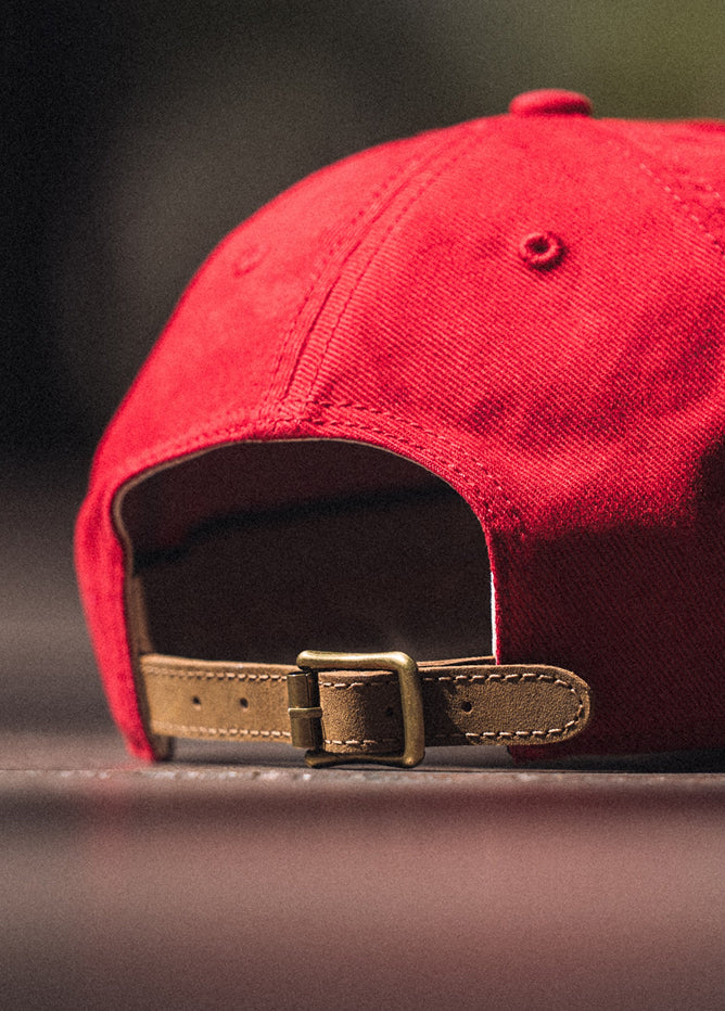 Red cap with a brown leather strap on a dark background