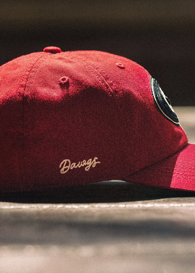 Red cap with 'Dawgs' embroidery on a dark background