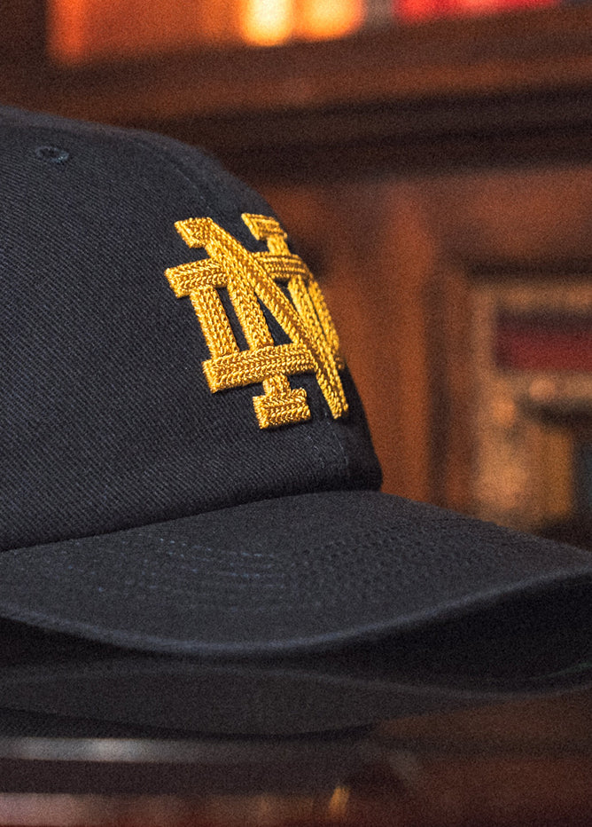 Black cap with gold embroidered logo on a blurred background