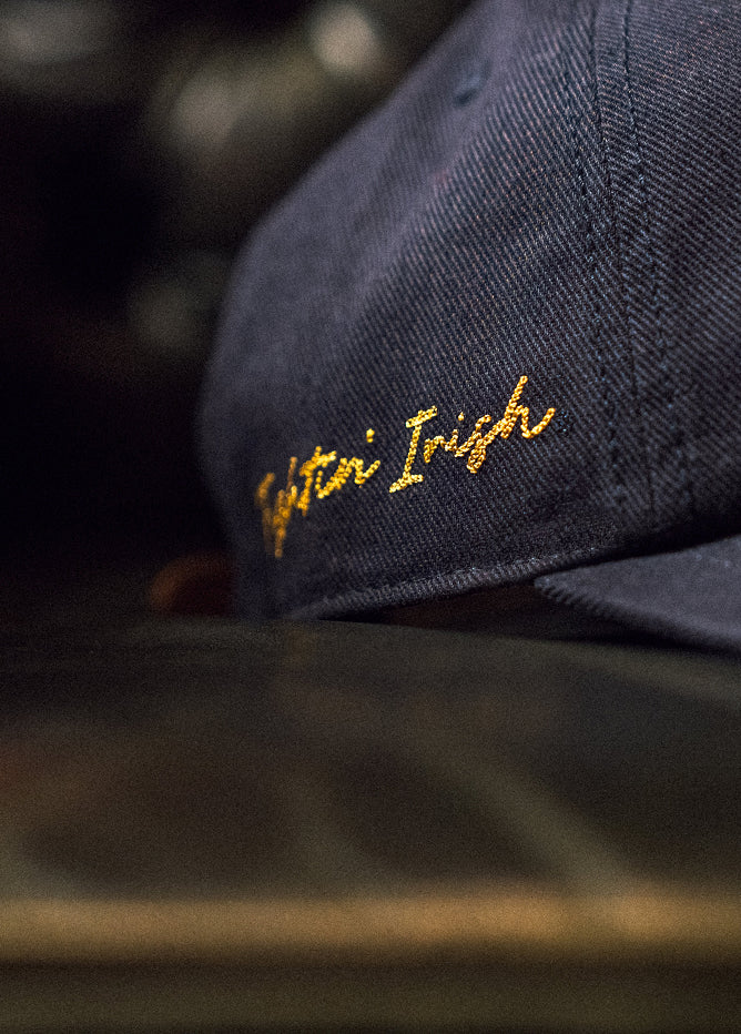 Navy blue cap with yellow embroidered text on a blurred background
