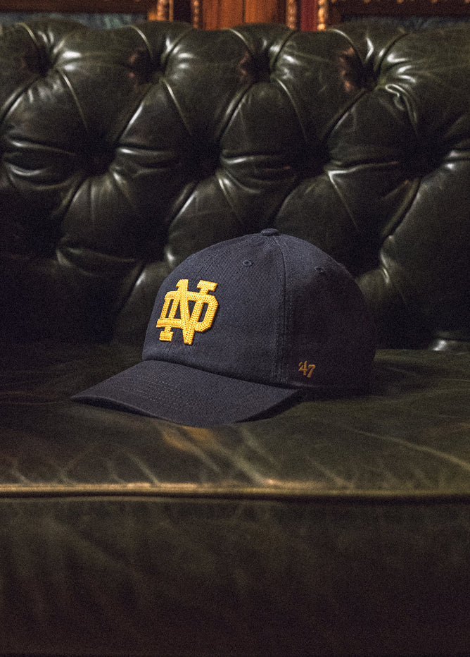 Navy blue cap with yellow logo on a dark leather couch