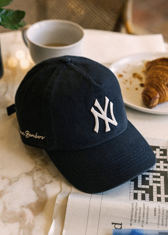 Black cap with white logo on a newspaper with a blurred background of a cafe setting.